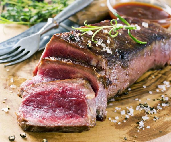 Pièce de côtes de boeuf de Bazas saignante et tranchée, servi sur une planche en bois au Restaurant La Table de Trois à Bordeaux